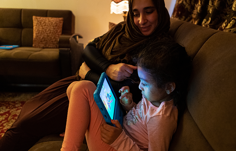 A photo of parent and children using tablet