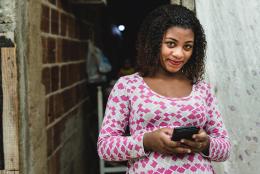 A women using a phone representing What the Tech: Can WhatsApp Support Program Delivery with Busy Families?